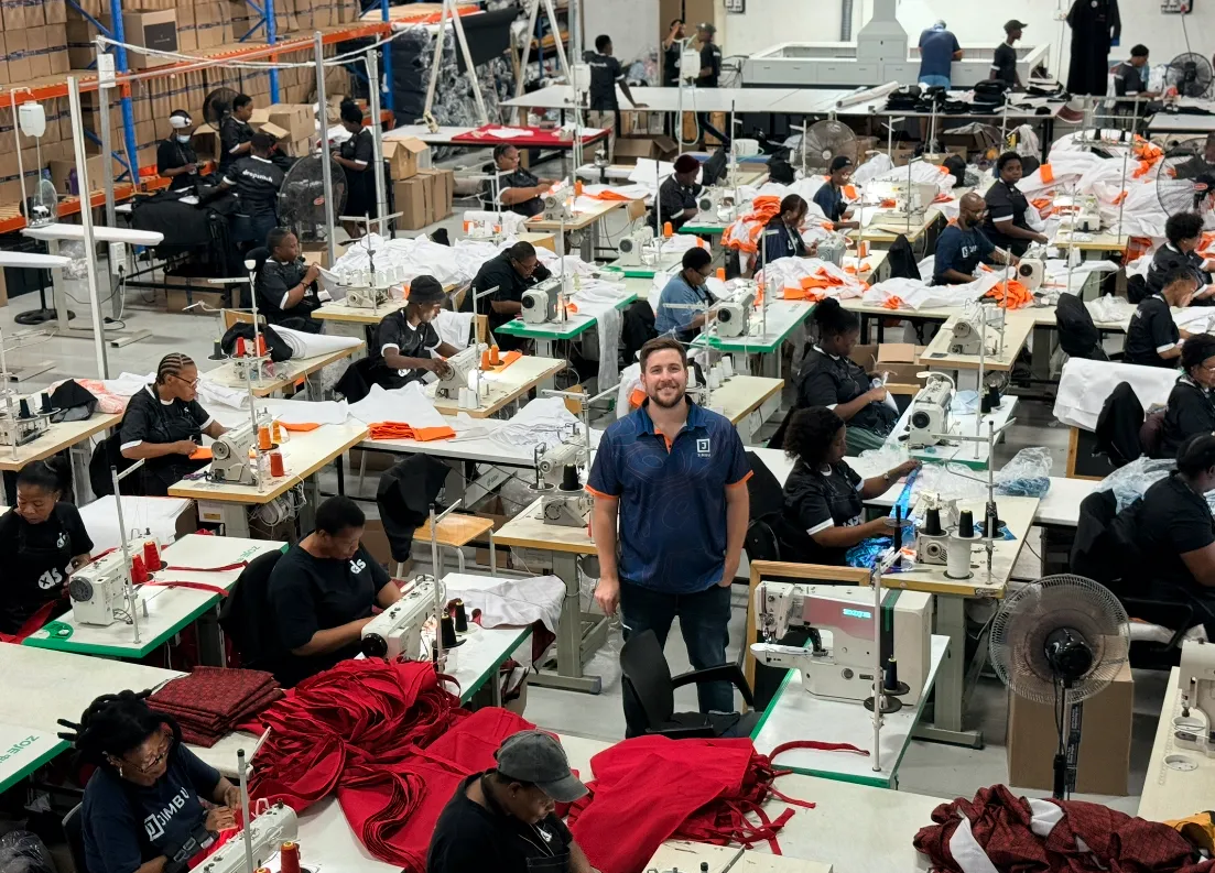 The busy JIMBU factory floor with machinists sewing branded garments
