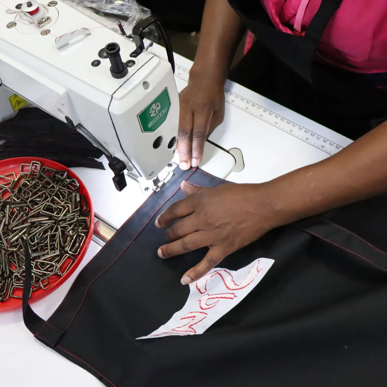 Learner stitching branded apparel on an industrial sewing machine