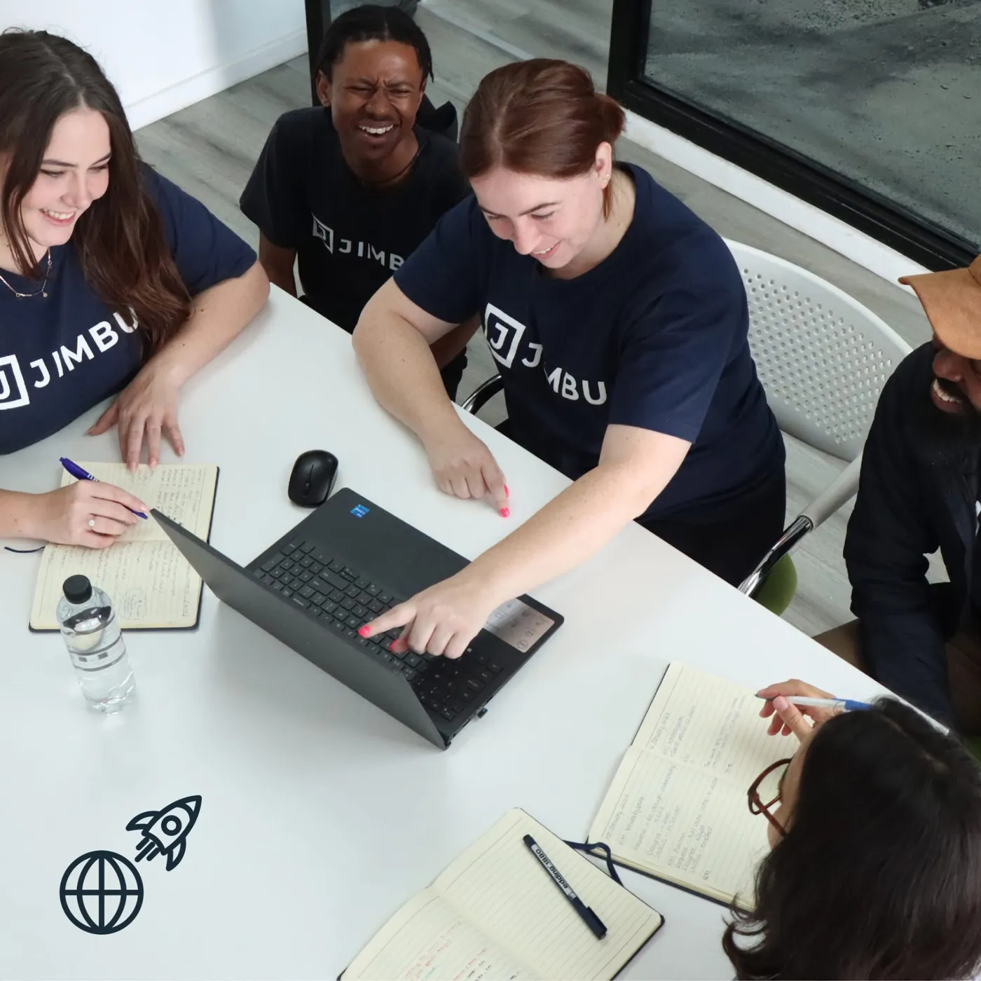 The JIMBU team working together around a laptop