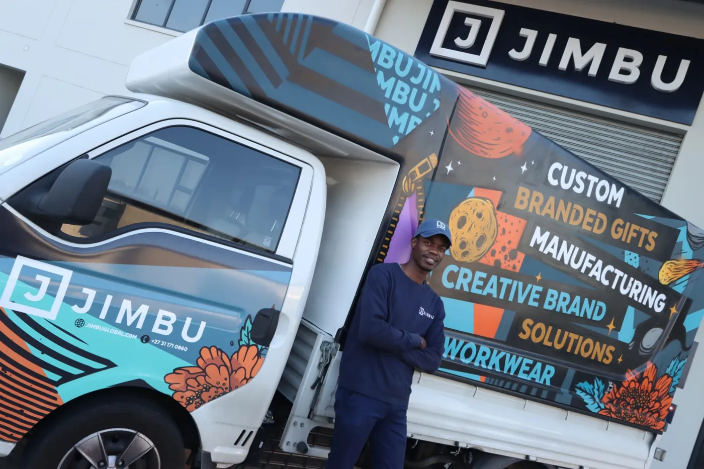 JIMBU team member in front of the branded JIMBU delivery truck and building