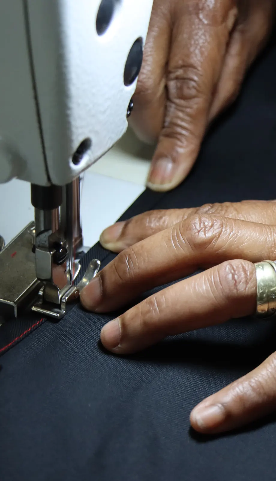 Close-up of hands guiding fabric through an industrial sewing machine
